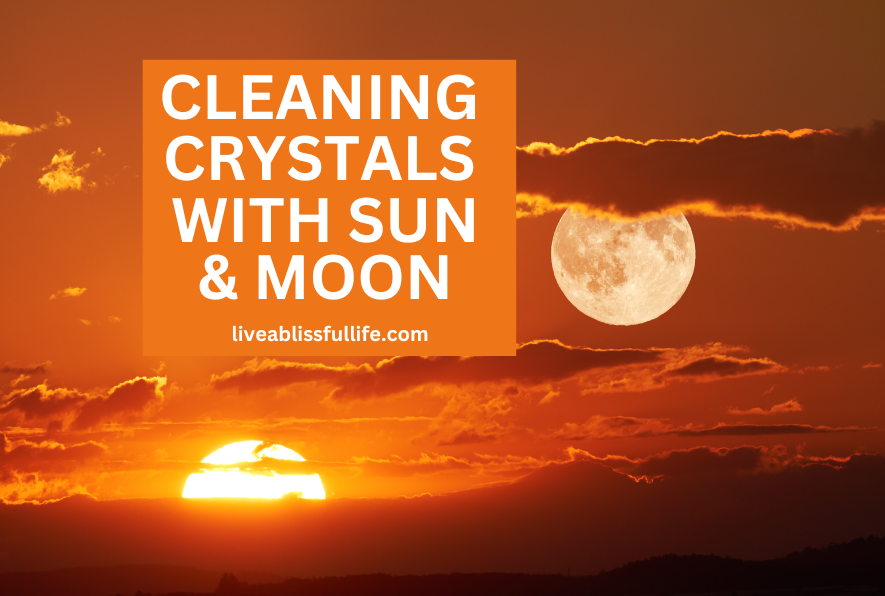 An orange sky with the sun setting and the moon rising; Text says "Cleaning crystals with sun and moon by liveablissfullife.com"